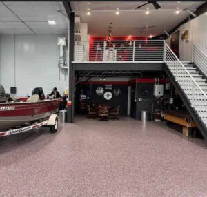 Car showroom/storage with boats and a staircase to a loft, featuring a red and gray interior.