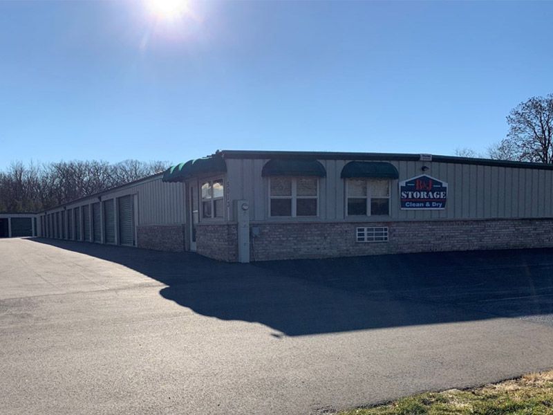 Low brick commercial building with green awnings beside an empty paved lot on a sunny day