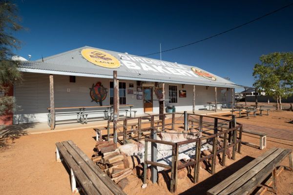 Bar building with benches and fire pit. Blue sky. Outback setting.
