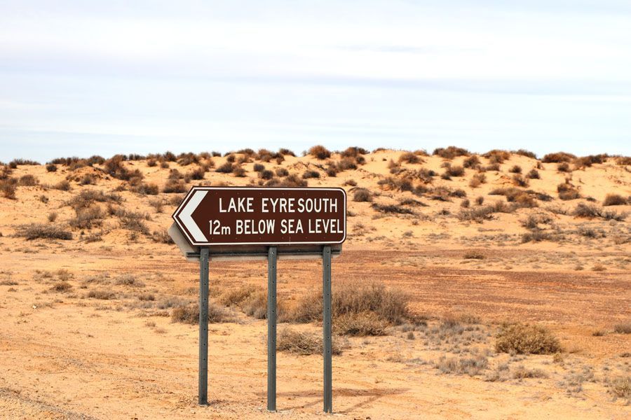 Sign pointing to Lake Eyre South, 12 meters below sea level, in arid landscape.