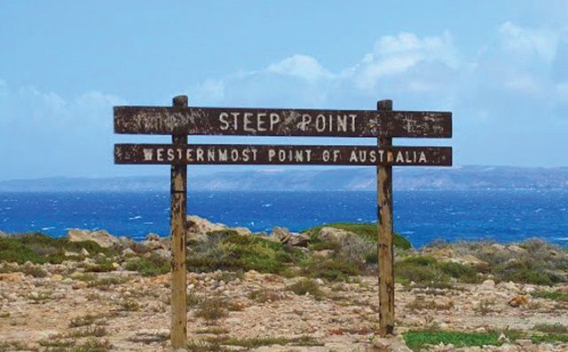 Sign at Steep Point, Westernmost Point of Australia, with ocean and blue sky in the background.