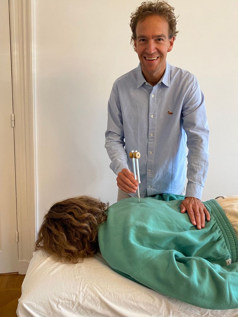Acupunctuur demonstratie met een stemvork, gericht op een specifiek acupunctuurpunt op de rug voor heling.