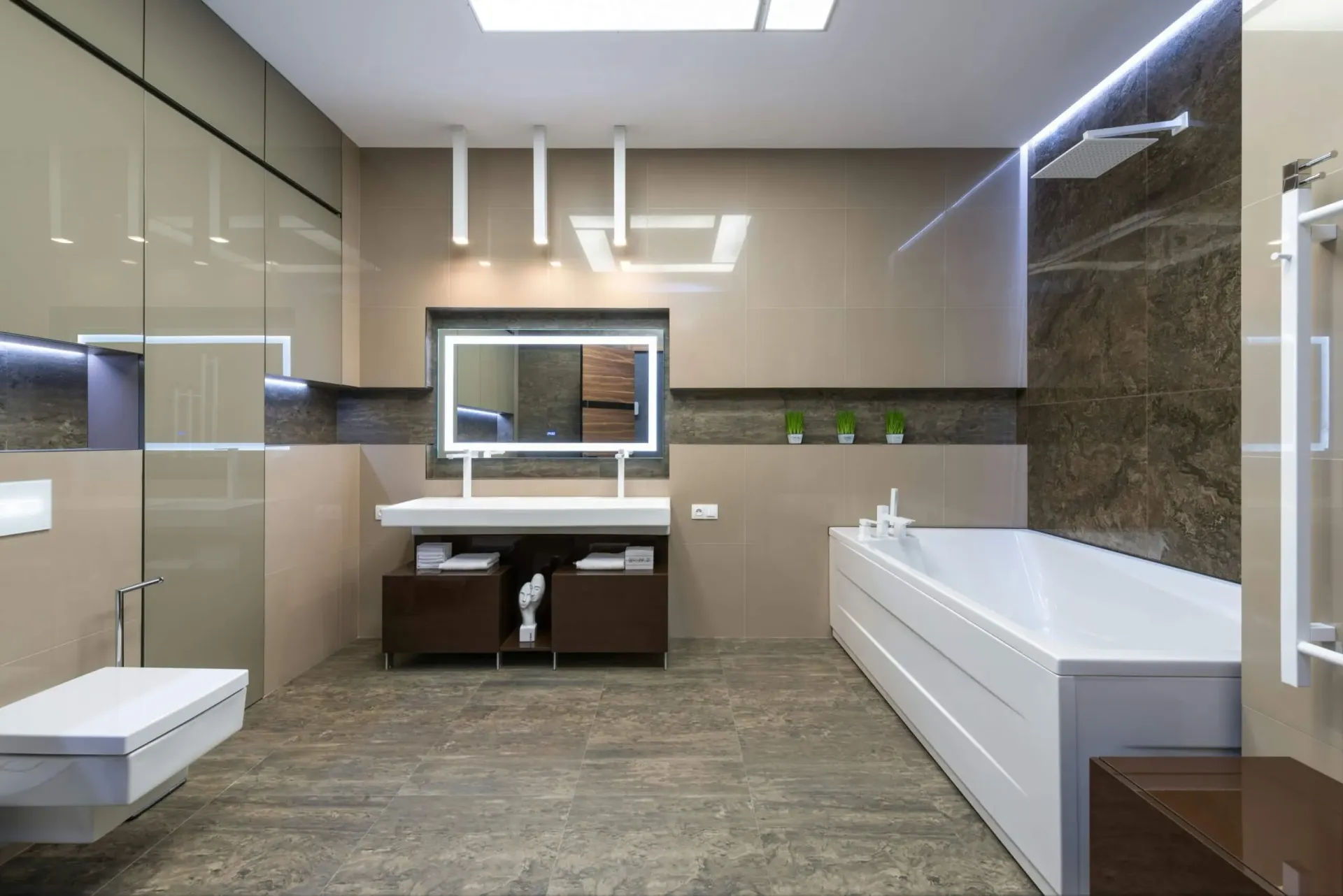 Modern bathroom with neutral tones, large bathtub, wall-mounted toilet, vanity with mirror, and shower.