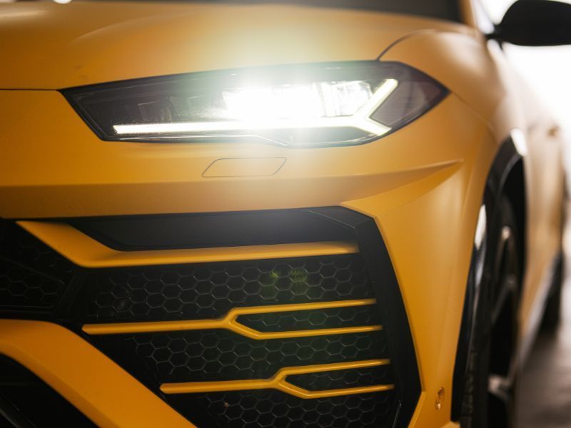 Close-up of a yellow sports car front grille and bright headlight