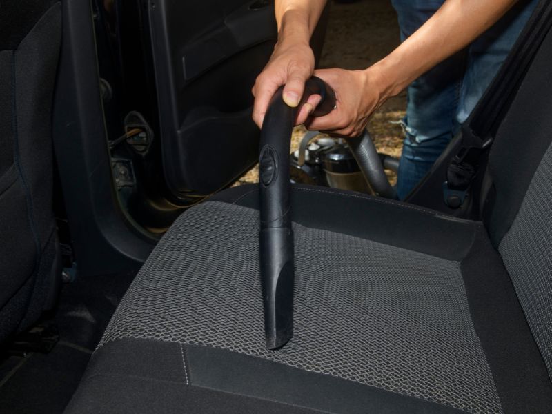 Vacuum nozzle cleaning a car’s front passenger seat