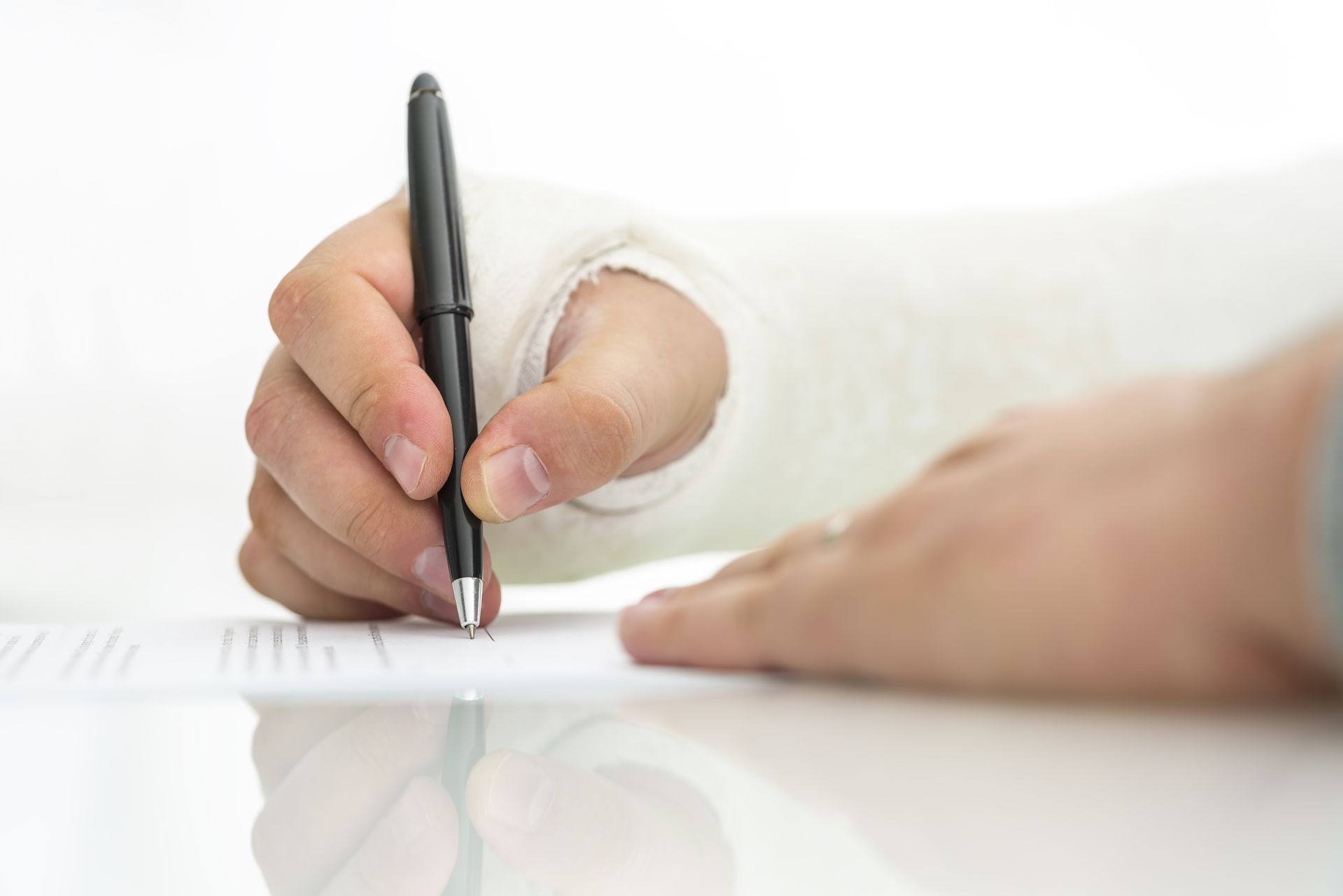 Hand writing on a white sheet with a black pen, hand in a white sleeve