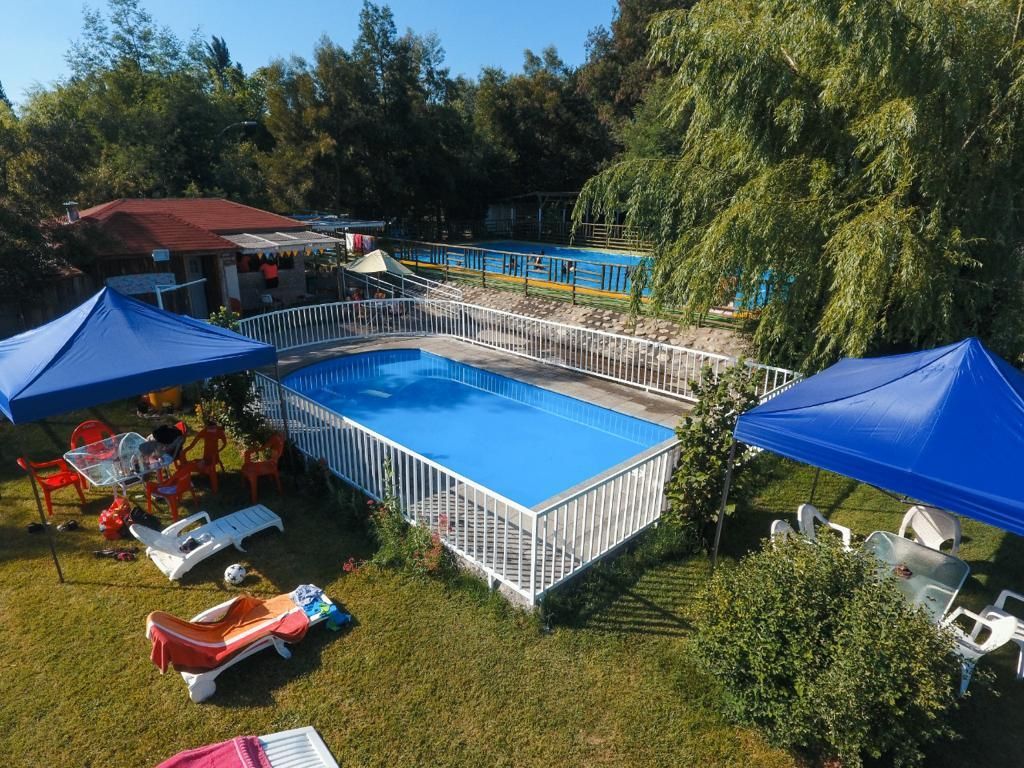 Una vista aérea de una piscina rodeada de carpas y sillas.