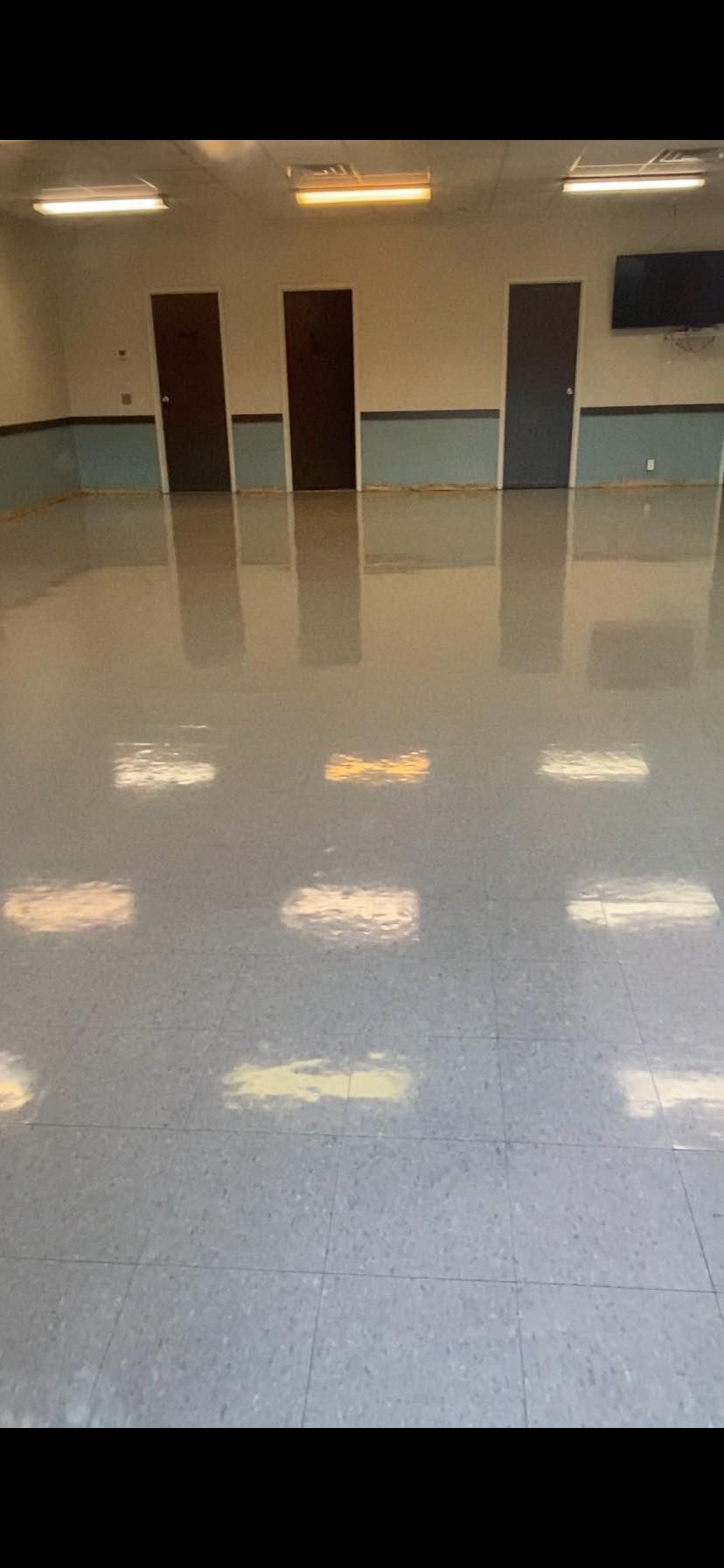 A large empty room with a shiny floor and doors.