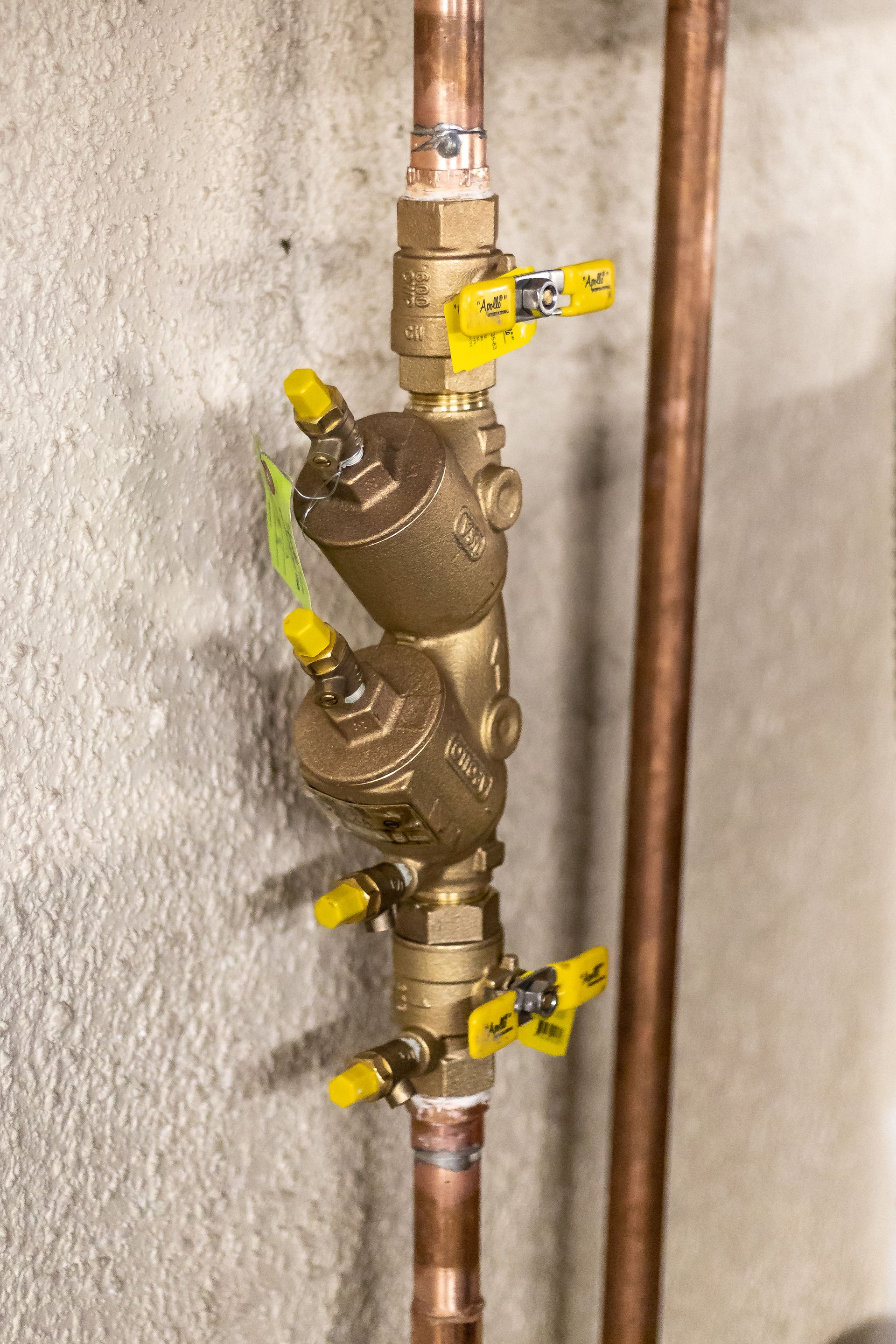 A close up of a copper pipe with yellow valves attached to it.