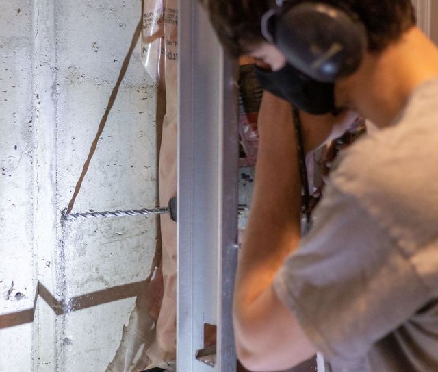 Person wearing headphones works on a wall panel during construction or repair.