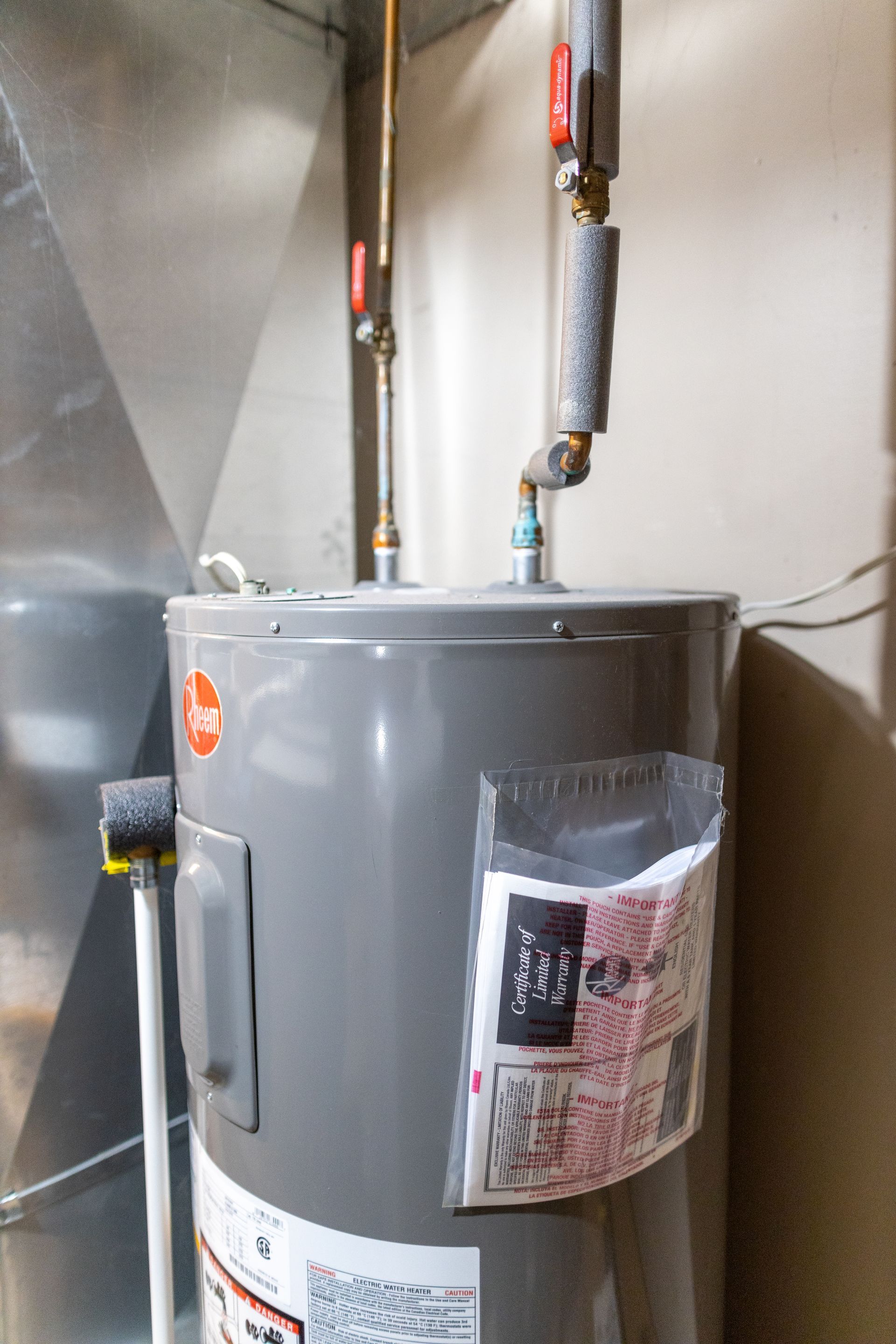 A gray water heater is sitting in a room next to a wall.