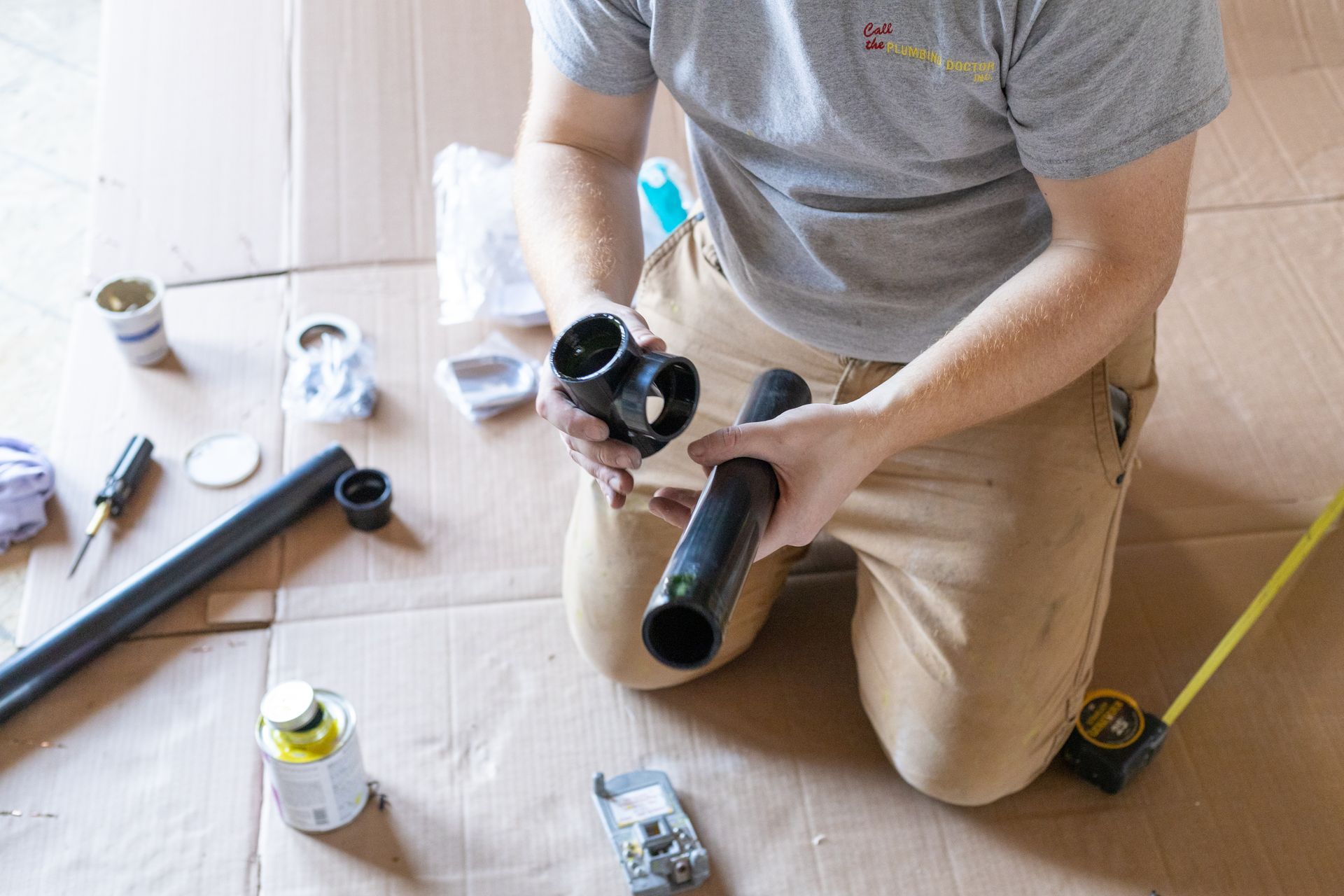 A man is kneeling down on the floor holding a pipe.