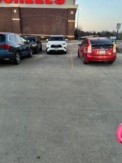 Cars parked in a paved lot in front of a store with red signage.