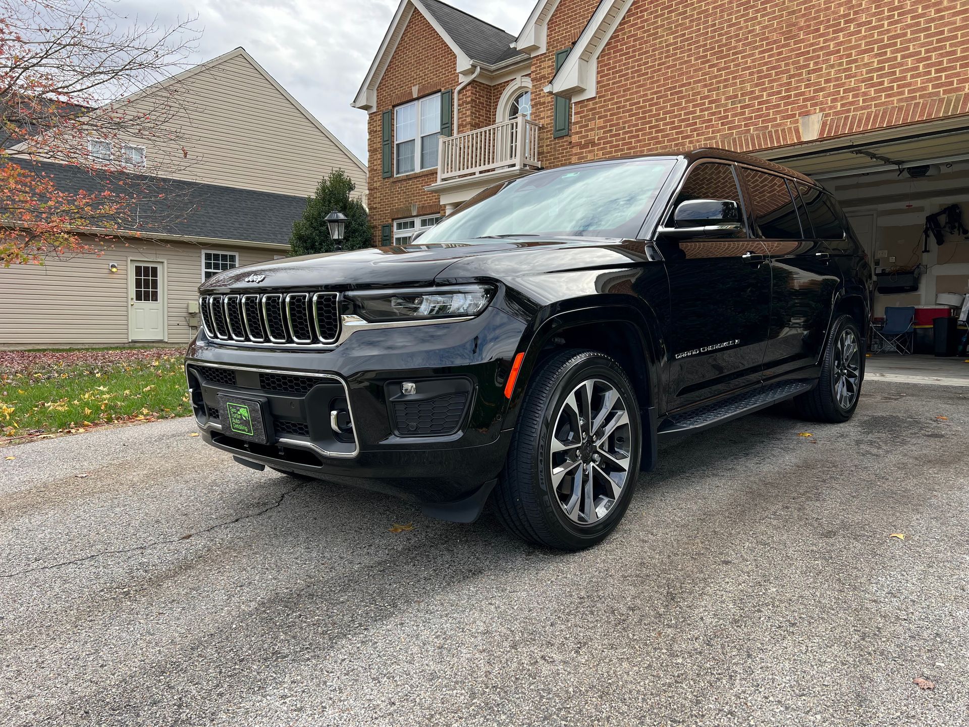 a black jeep grand cherokee is parked in front of a brick house .
