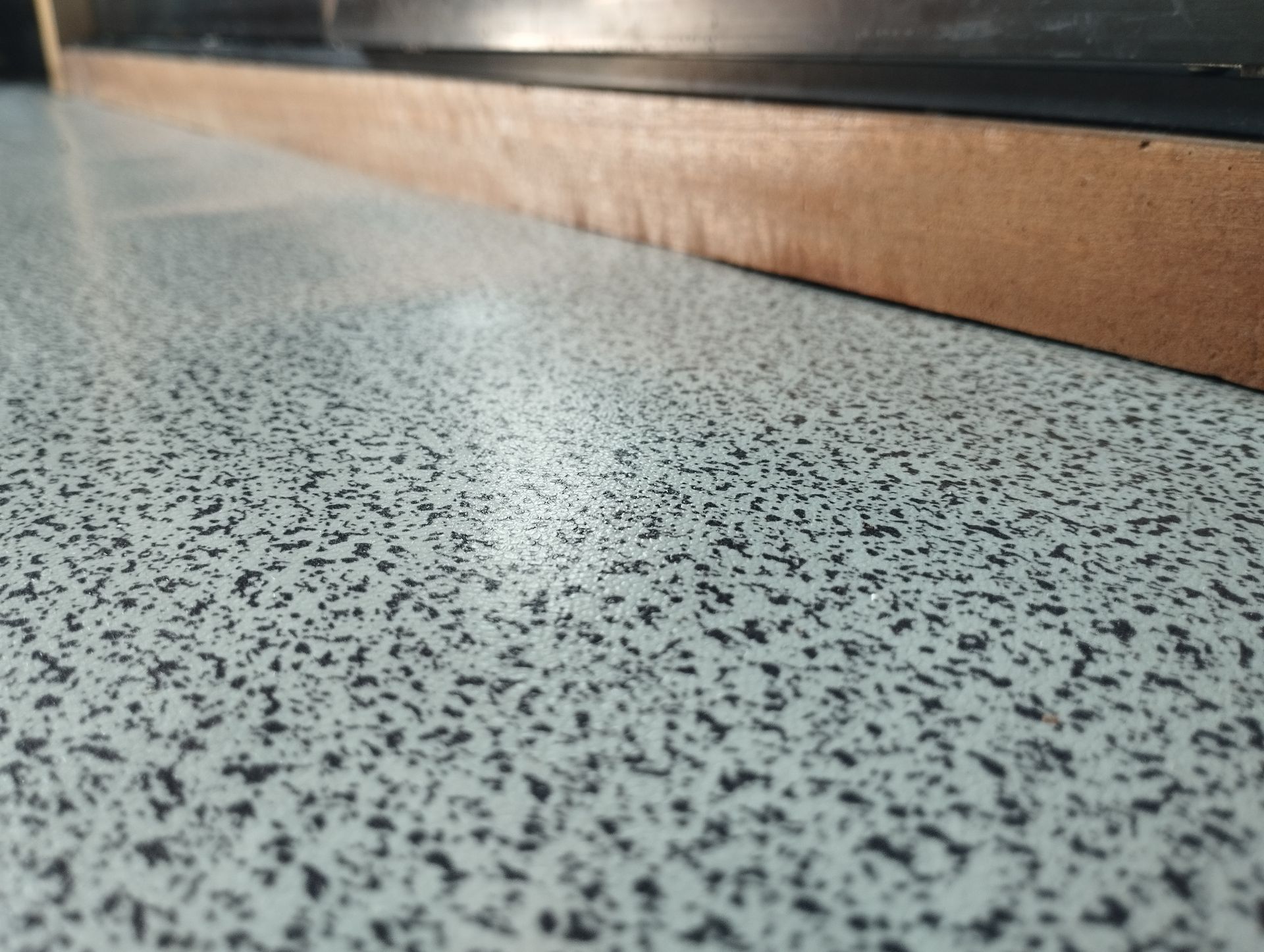 Close-Up Of A Speckled, Light-Gray Countertop With A Wooden Edge — CPAINT In Taree, NSW