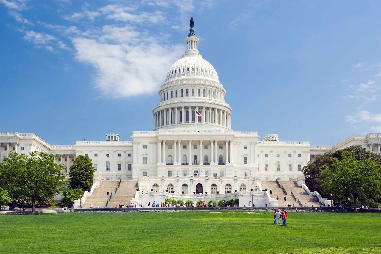 US Capitol Building with green lawn and blue sky.