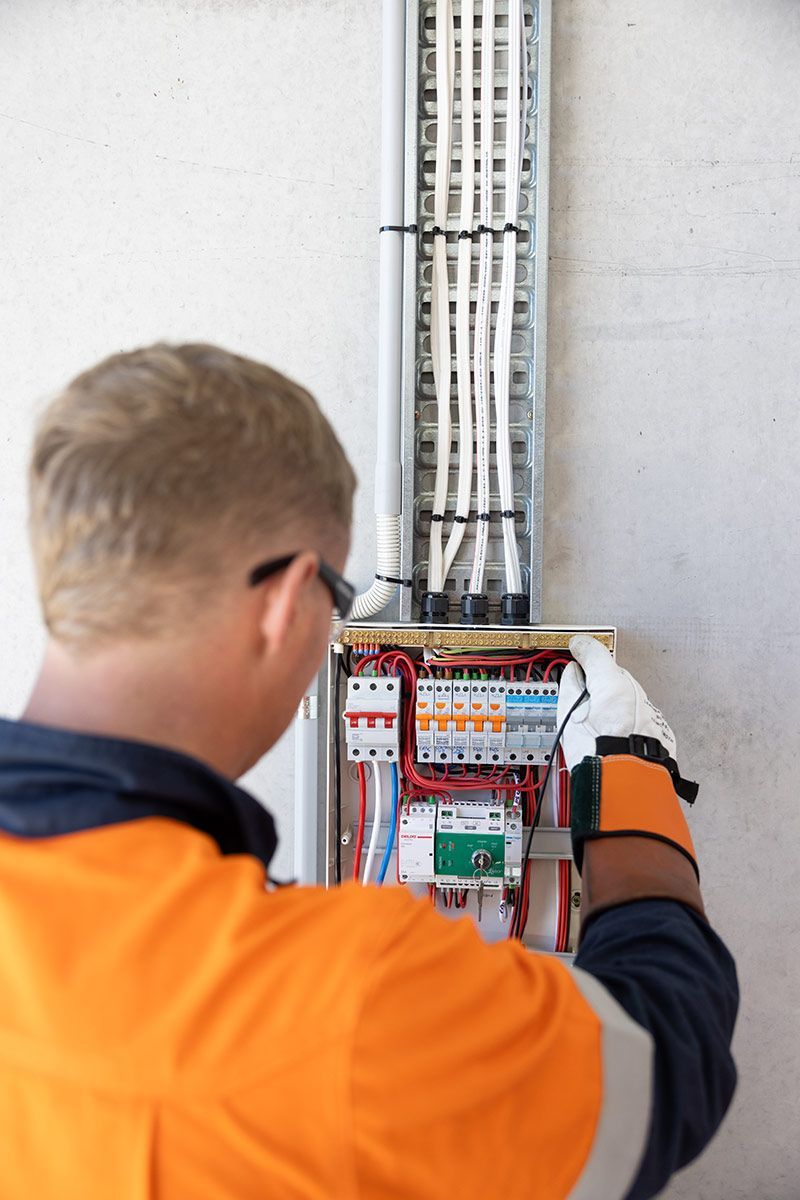 A Man is Working on an Electrical Box on a Wall — Macquarie Electric in Dubbo, NSW
