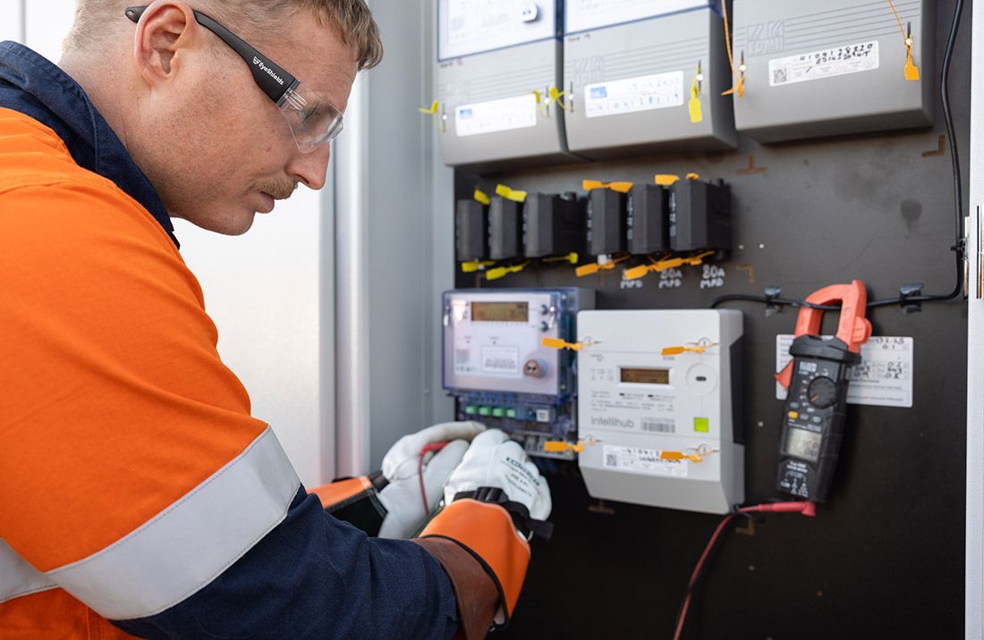 A Man is Working on an Electrical Panel With a Multimeter — Macquarie Electric in Mudgee, NSW