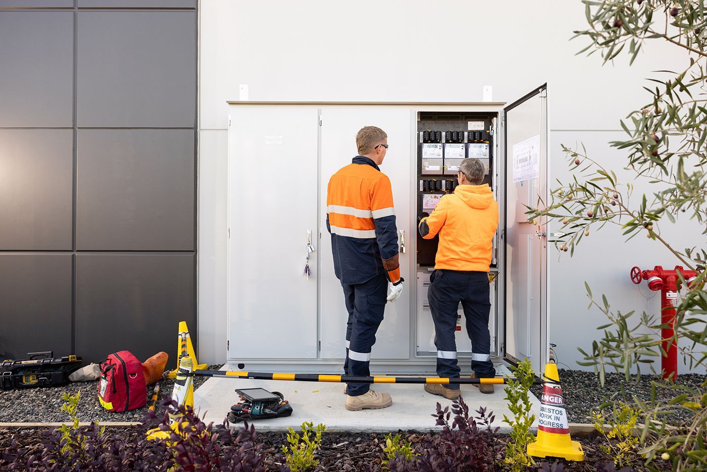 Two Men Are Sitting at a Table With a Laptop — Macquarie Electric in Dubbo, NSW