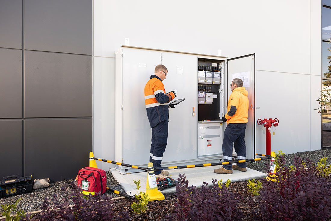 Two Men Are Working on a Building Outside — Macquarie Electric in Dubbo, NSW