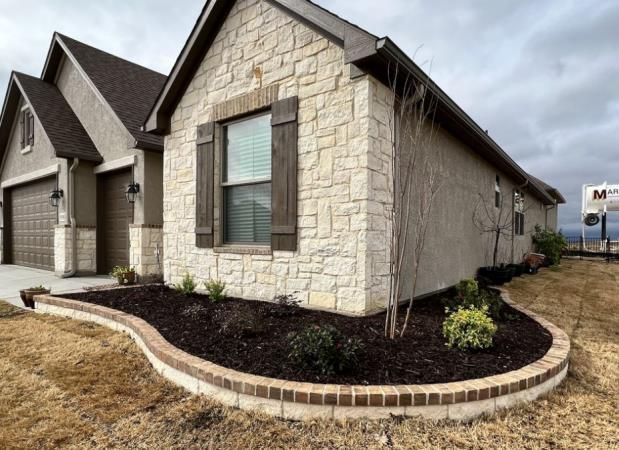 a brick house with a lush green lawn in front of it