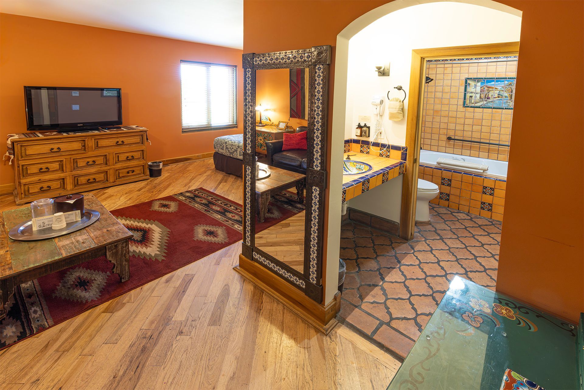 Hotel room with living area, bathroom visible through an archway.
