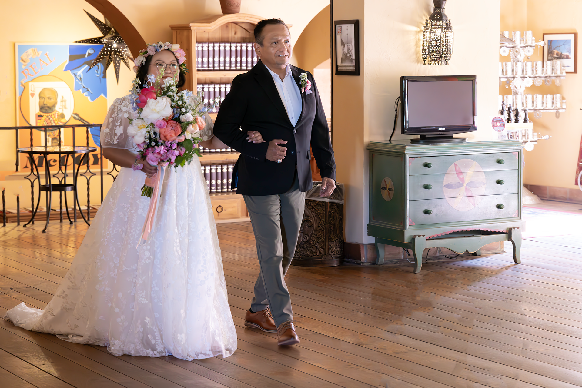 Bride in white dress with floral bouquet walks with man in suit at a wedding.