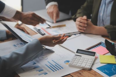 Un grupo de personas está sentada a una mesa con papeles y una calculadora.