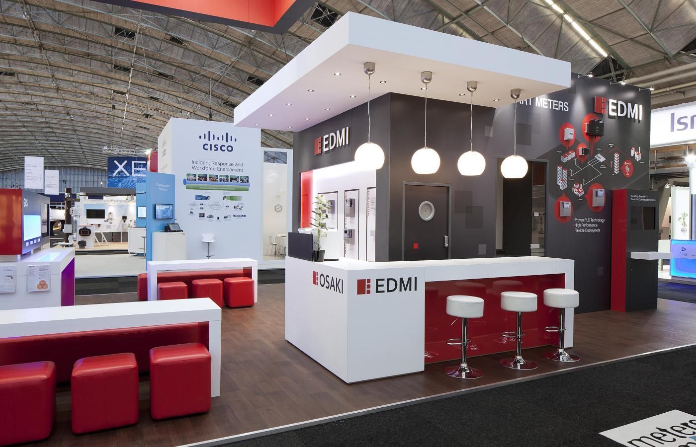 EDMI trade show booth with white and red accents, displaying products. People are not visible.