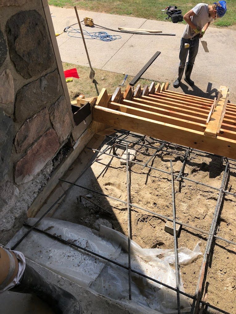 A man is working on a wooden structure in the dirt.