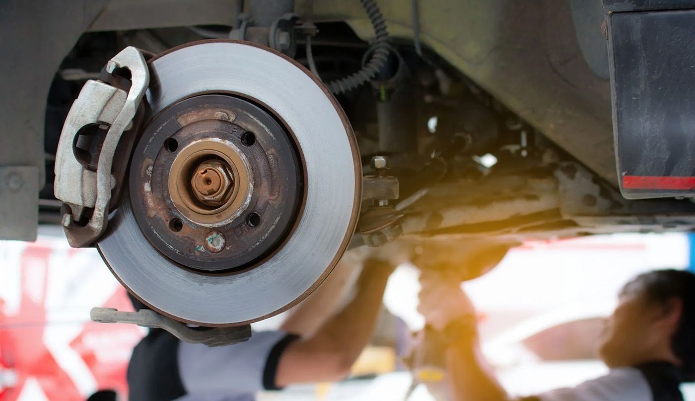 A man is working on the brake disc of a car.