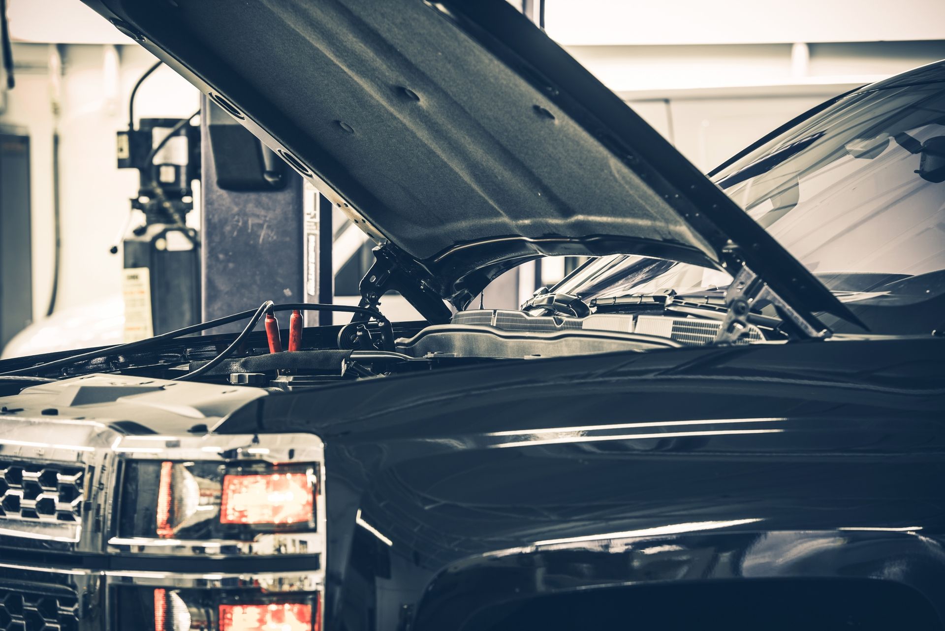 A black truck with its hood open in a garage.