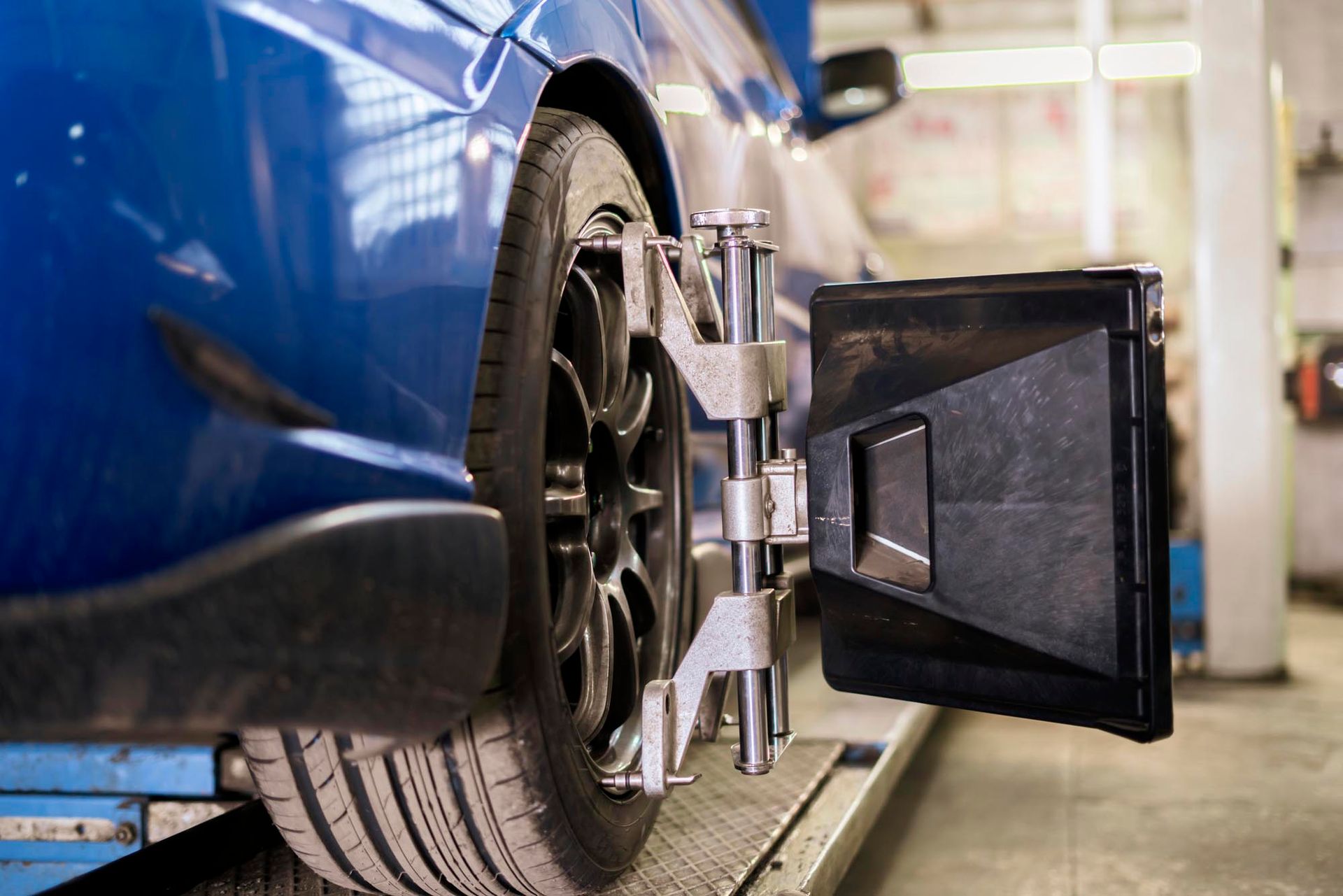 A blue car is being adjusted by a machine in a garage.
