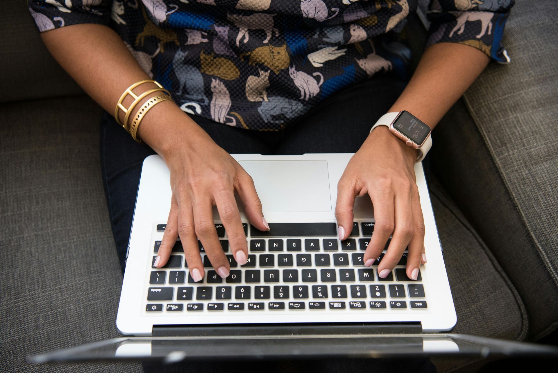 A professional sits at a desk with a laptop and coffee, writing on paper while speaking on a mobile phone.