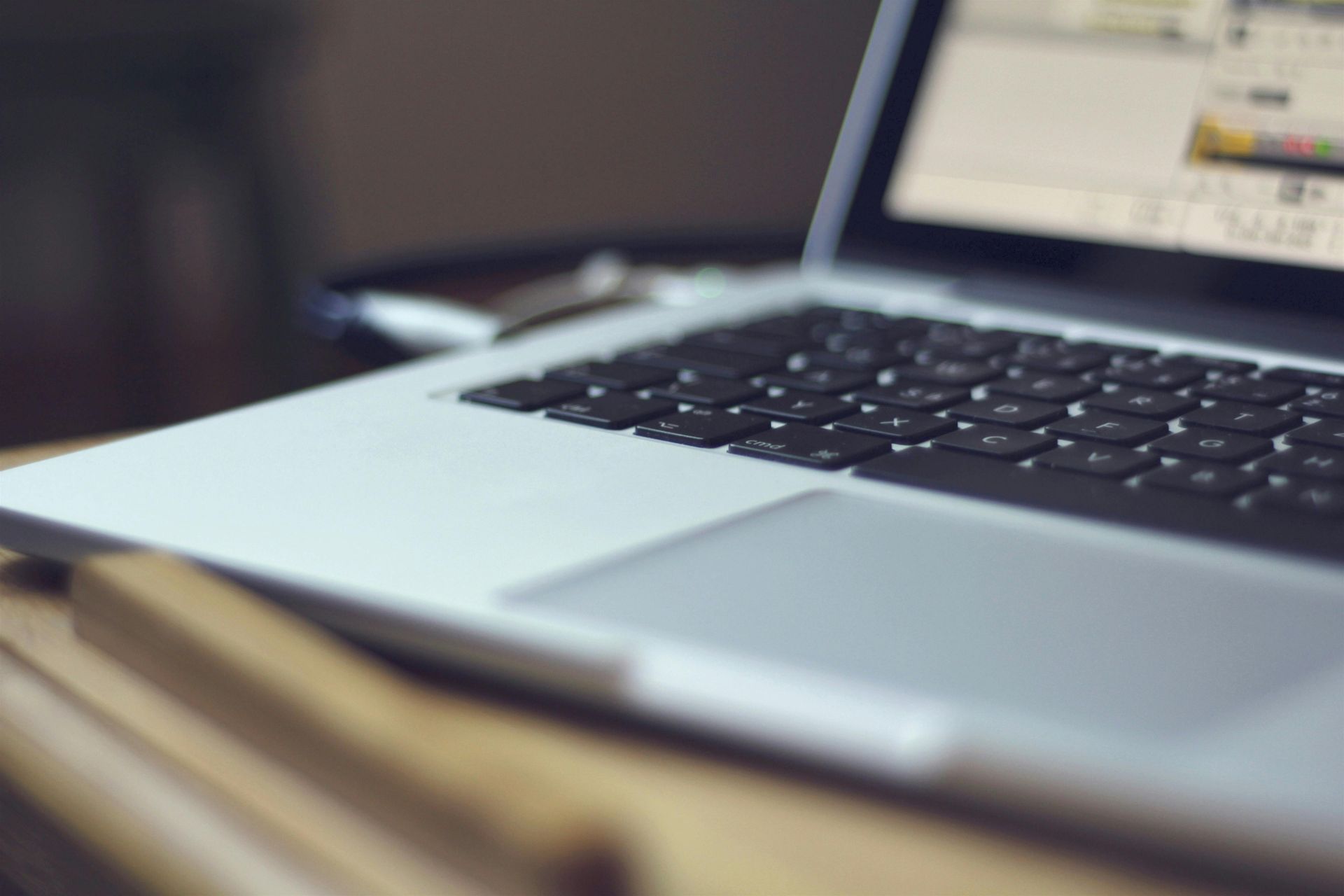 Silver laptop open on a wooden surface, keyboard visible, screen displaying content.