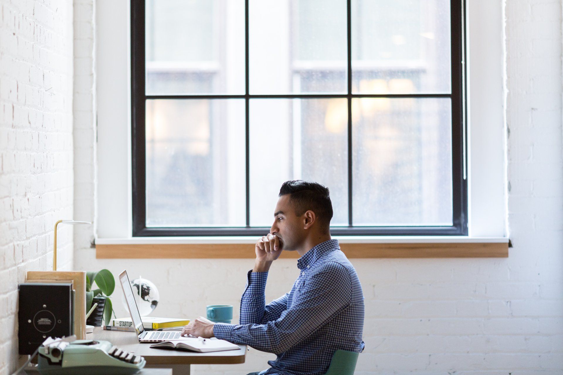 A Virtual Assistant is sitting at a desk in front of a computer.