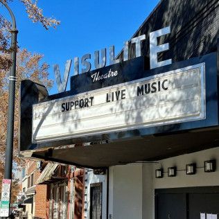 The marquee of the Visulite Theatre under a clear blue sky, displaying the message 