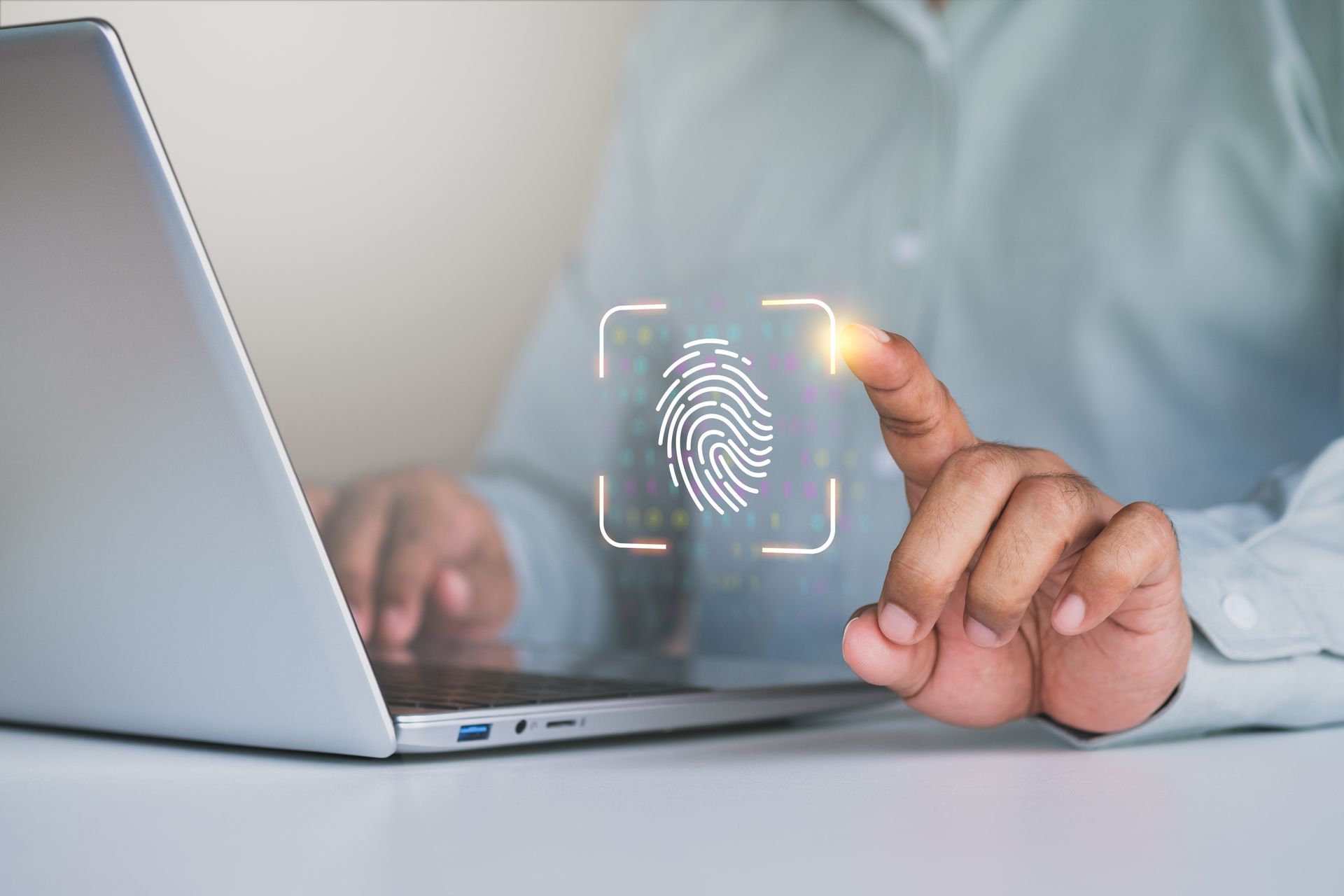 Person using fingerprint scan on a laptop for digital security, indoors.