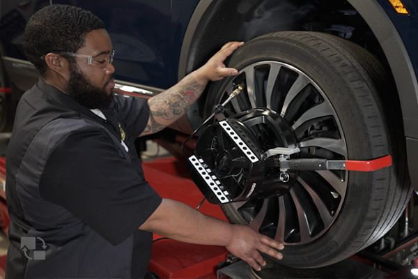 Mechanic aligning a car tire with a machine in a garage.