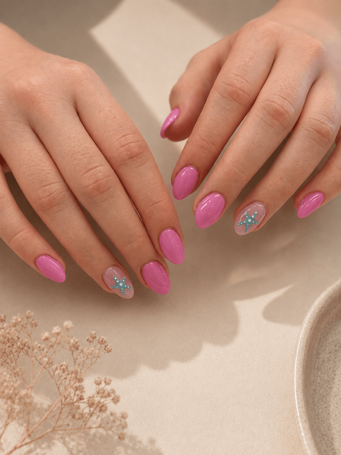 Hands with pink and glittery manicured nails resting on a beige surface