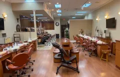 Empty nail salon with manicure stations, orange chairs, and bright overhead lights