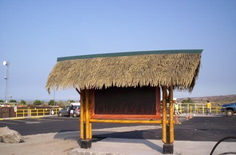 A small hut with a thatched roof in a parking lot