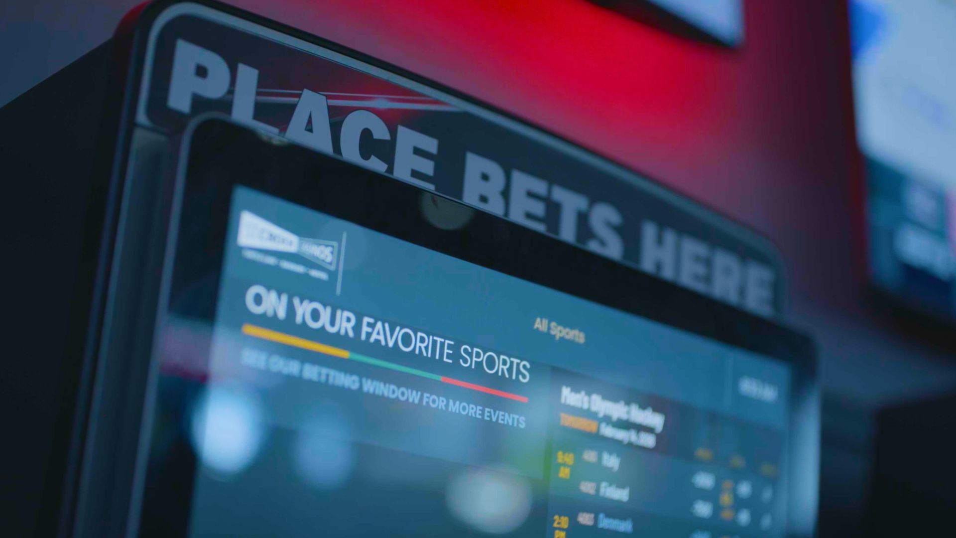 Row of black video slot machines with glowing screens and “Bet Here” signs in a casino