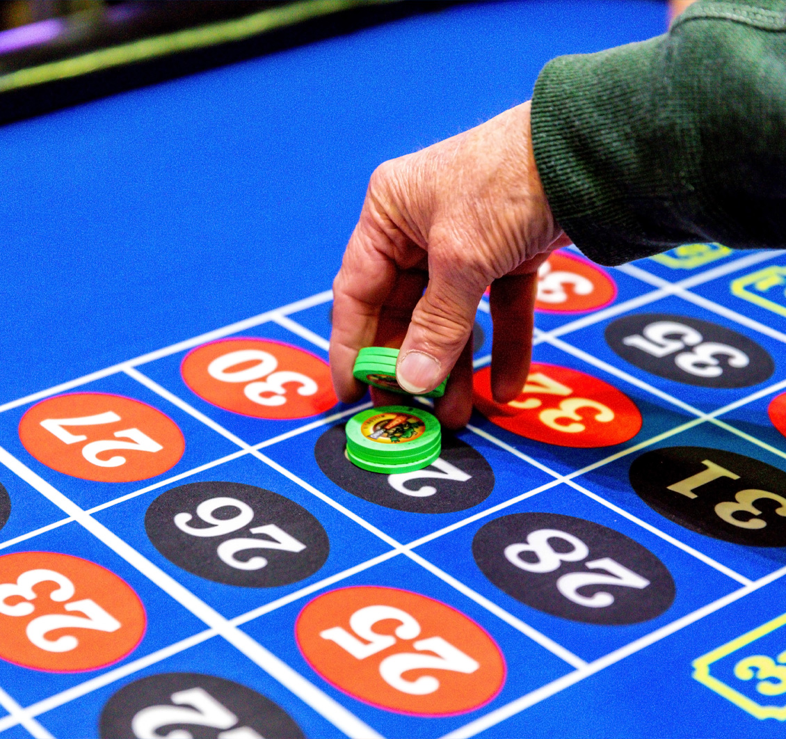 Hand placing a roulette chip on a blue numbered betting board