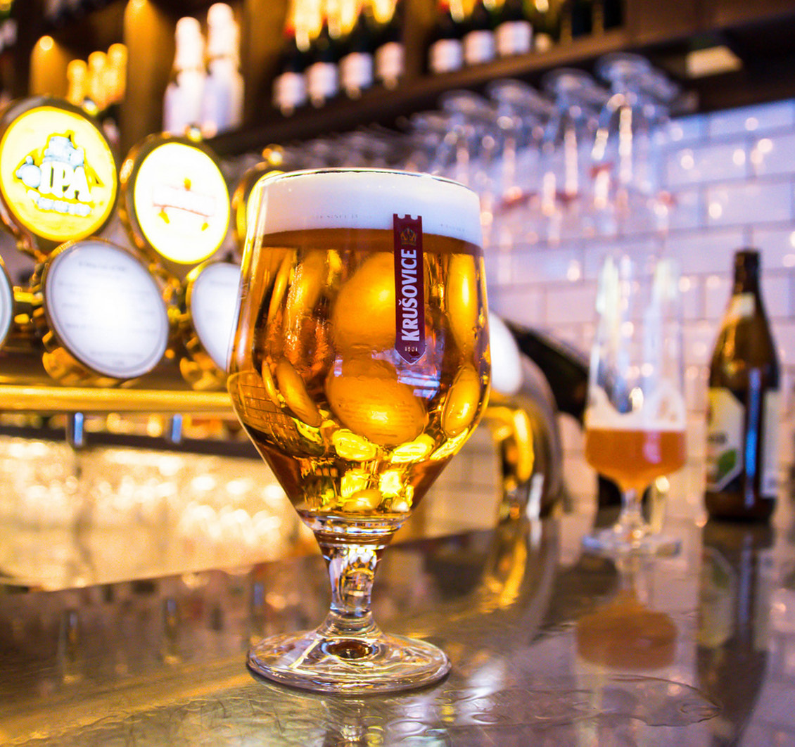 Glass of beer on a bar counter with glowing taps in the background