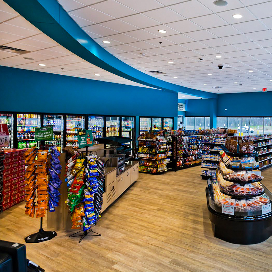 Bright convenience store interior with snacks, drinks, and refrigerated cases along blue walls