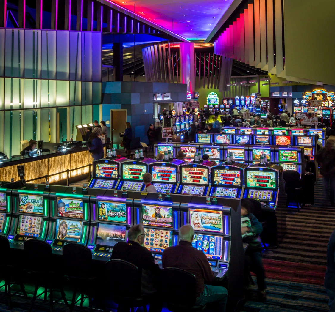 Bright casino floor with rows of glowing slot machines under colorful neon lighting