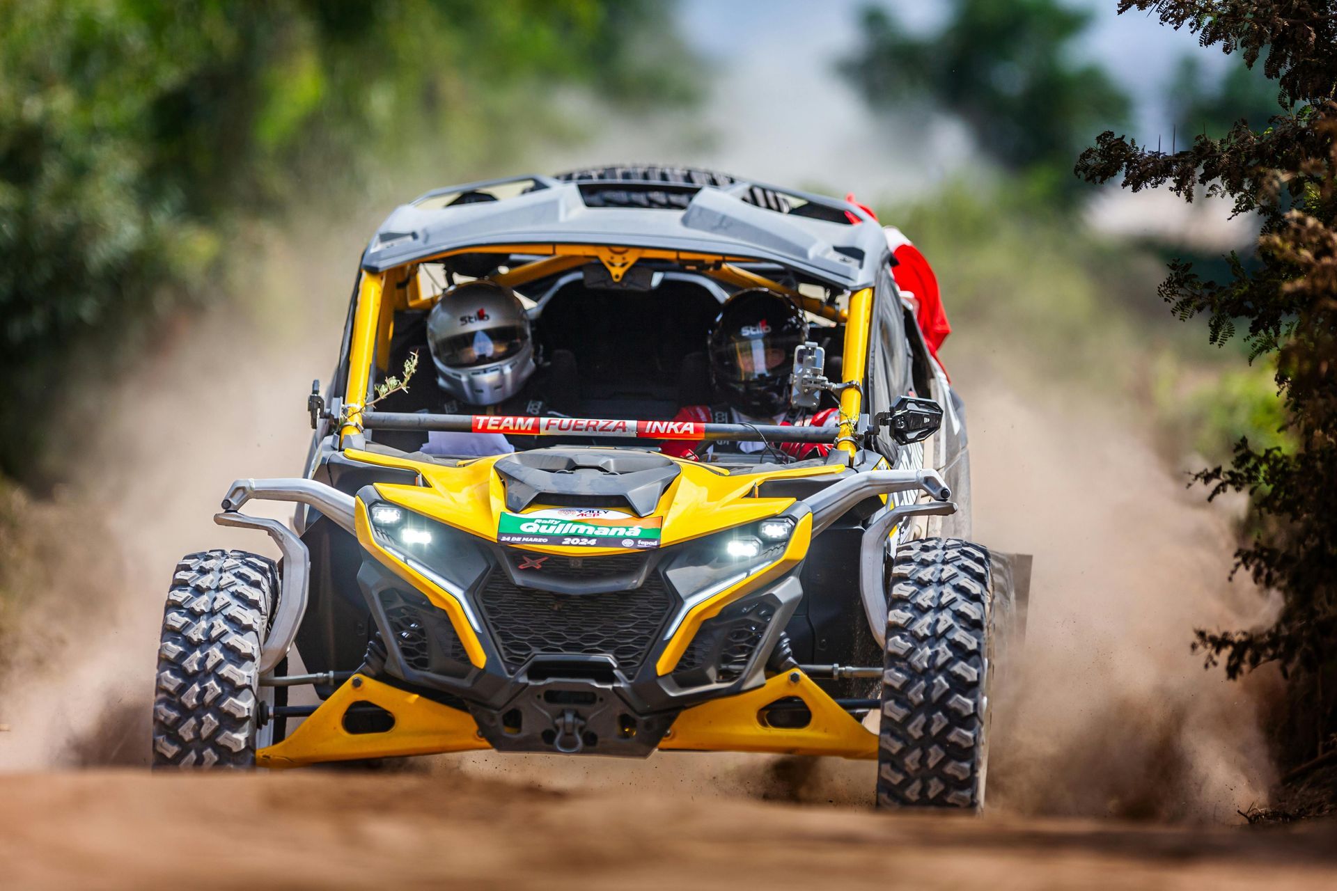 Off-road buggy racing through a dirt trail, kicking up dust, with a yellow-and-black front end
