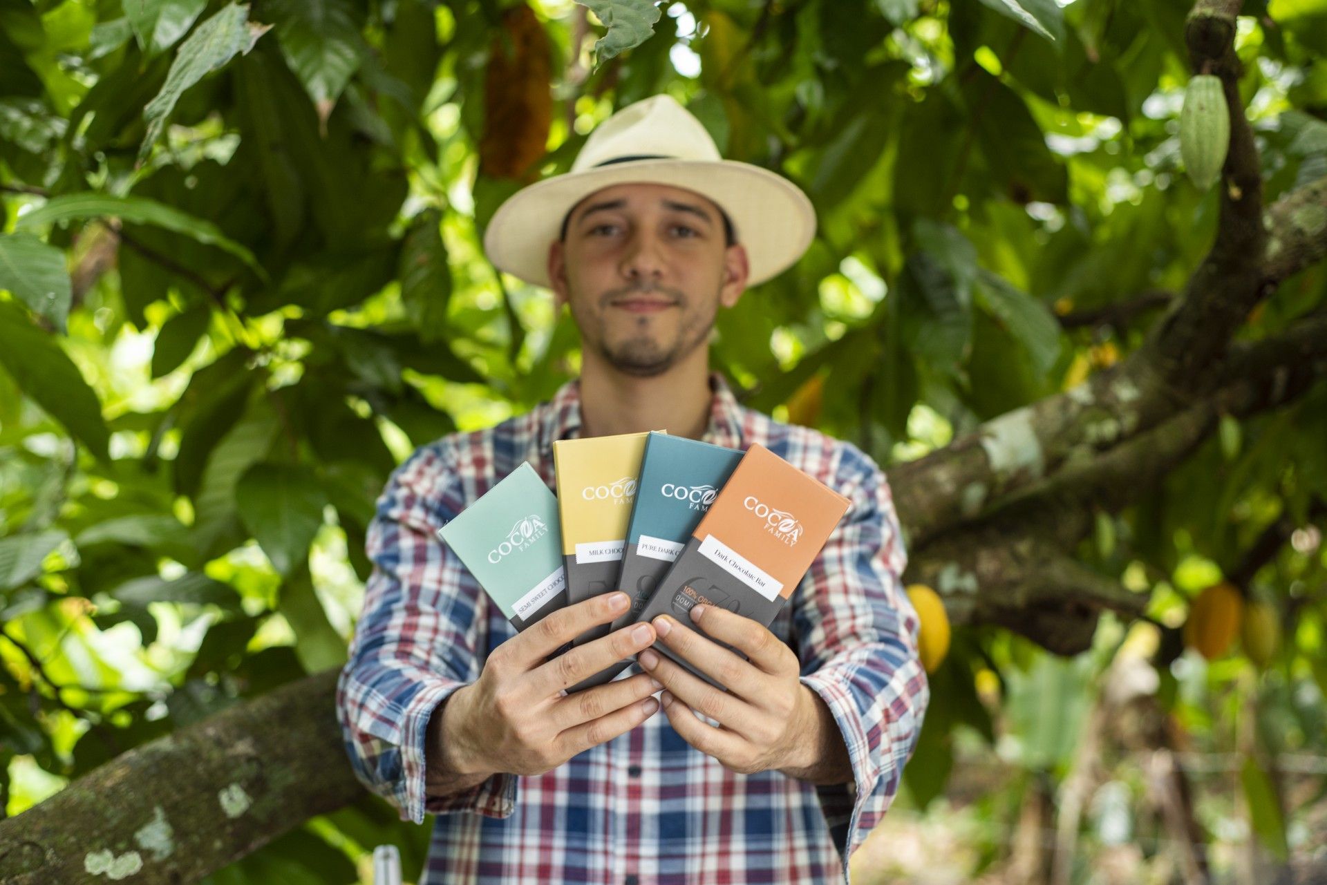 A man in a hat is holding four bars of chocolate