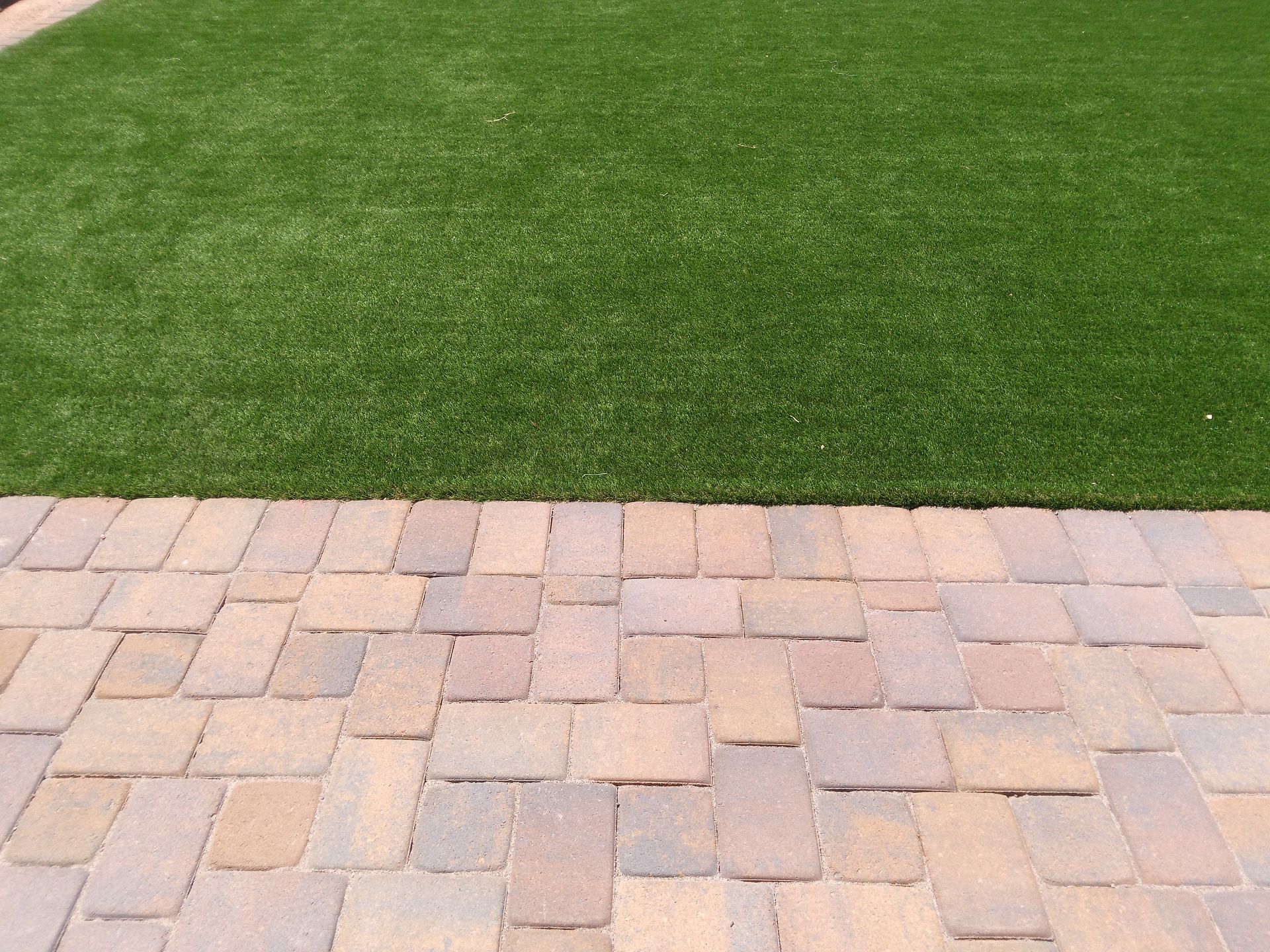A backyard makeover with pink pavers and artificial turf